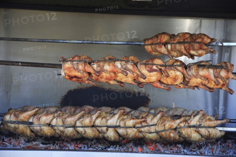 Albania, Tirane, Tirana, Spit-roasted chicken cooking over hot embers in the Avni Rustemi Market.
