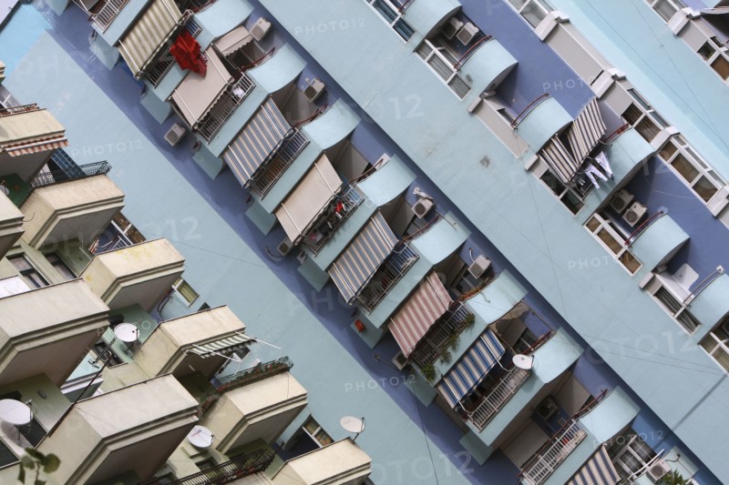 Albania, Tirane, Tirana, Angled view of balconies  striped awnings and satellite dishes on blue painted exterior facade of apartment block.