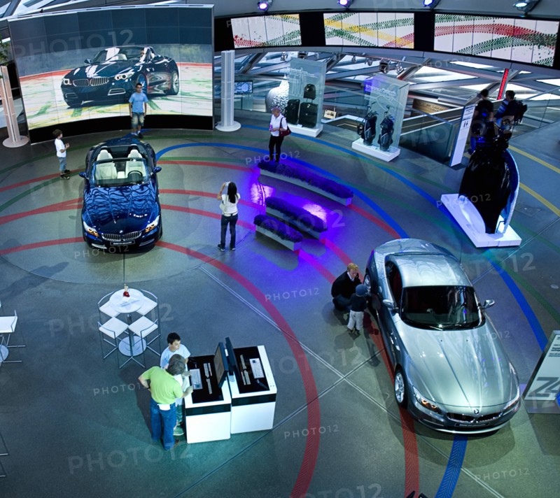 BMW Welt. Elevated view over showroom floor with people examining BMW cars. Photo : Hugh Rooney