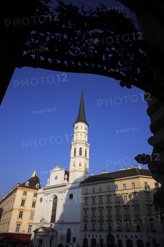 Angled view St Michaels Church exterior facade and spire against blue sky framed by decorative metal arch. Photo: Bennett Dean