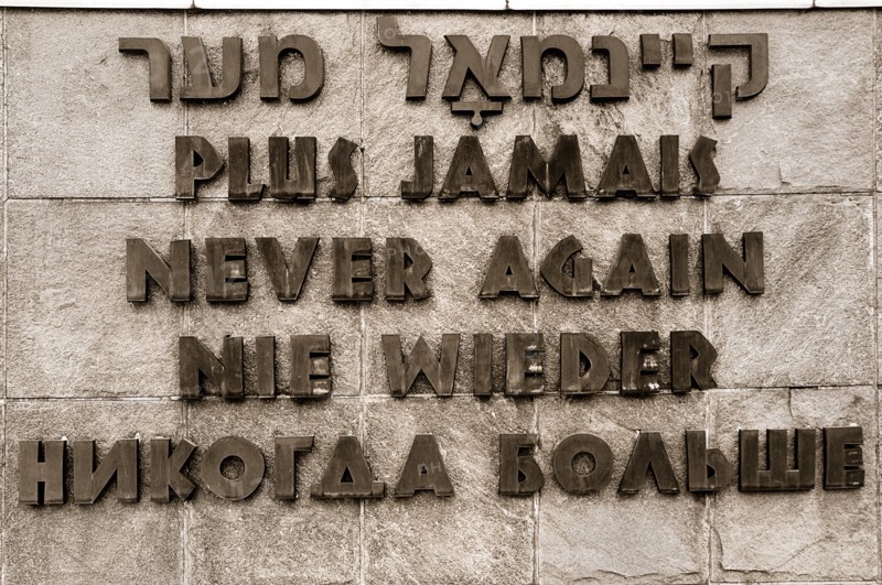 Dachau World War II Nazi Concentration Camp. Sign written in Hebrew French English German and Russian that reads Never Again. Photo: Hugh Rooney