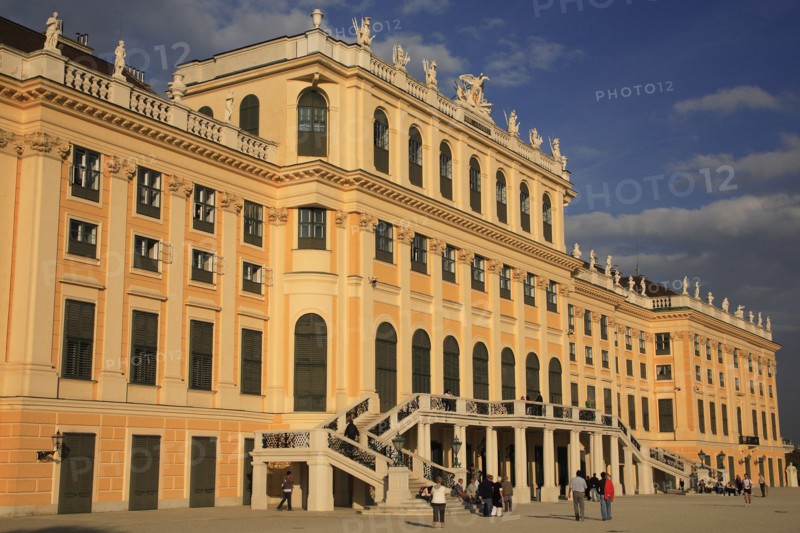 Schonnbrunn Palace. Angled part view of exterior facade with tourist visitors in courtyard and on steps and balcony.. Photo: Bennett Dean