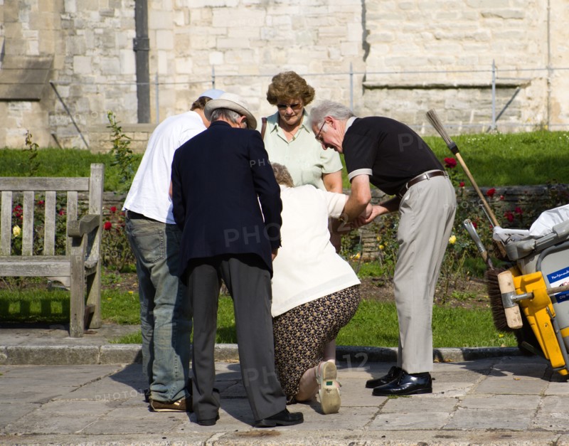 People helping an elderly lady to stand up after she has fallen on the pavement sidewalk outside the Anglican Cathedral in Old Portsmouth. Photo: Paul Seheult