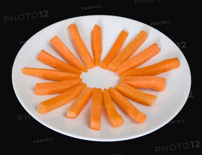 Slices of raw uncooked carrot on a white plate against a black background. Photo: Paul Seheult