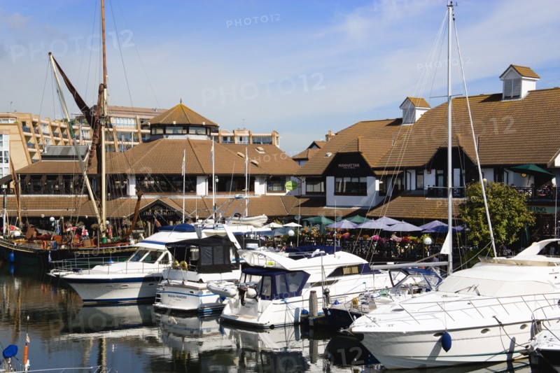 Port Solent Boats moored in the marina with people sitting at restaurant tables beyond beside a pub and housing apartments. Photo: Paul Seheult