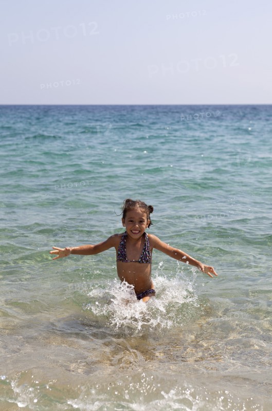 Young smilling girl playing at the sea throwing water and laughing. Photo: Athanasios Papadopoulos