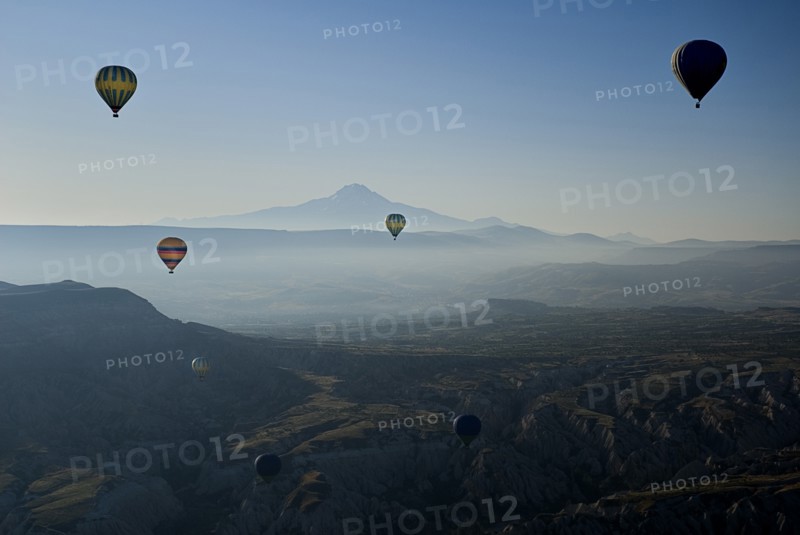 Early morning with hot air balloons in flight mist drifting across landscape and Mount Erciyes in the background. Photo : Hugh Rooney