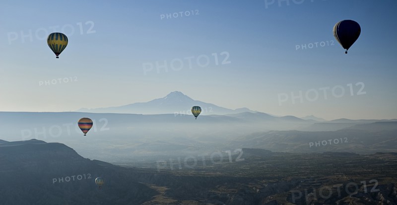 Early morning with hot air balloons in flight mist drifting across landscape and Mount Erciyes in the background. Photo: Hugh Rooney