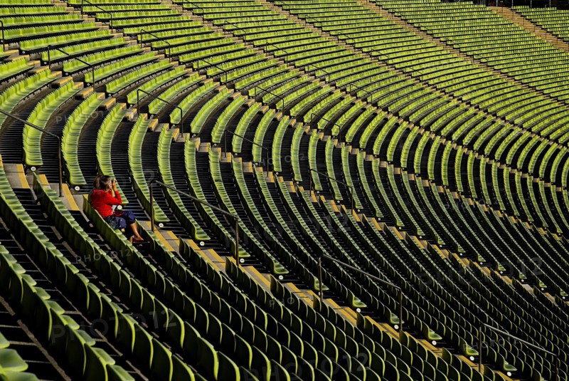 Olympic Stadium. Curved section of bright green seating in the stadium with seated figure centre left of image. Photo: Hugh Rooney