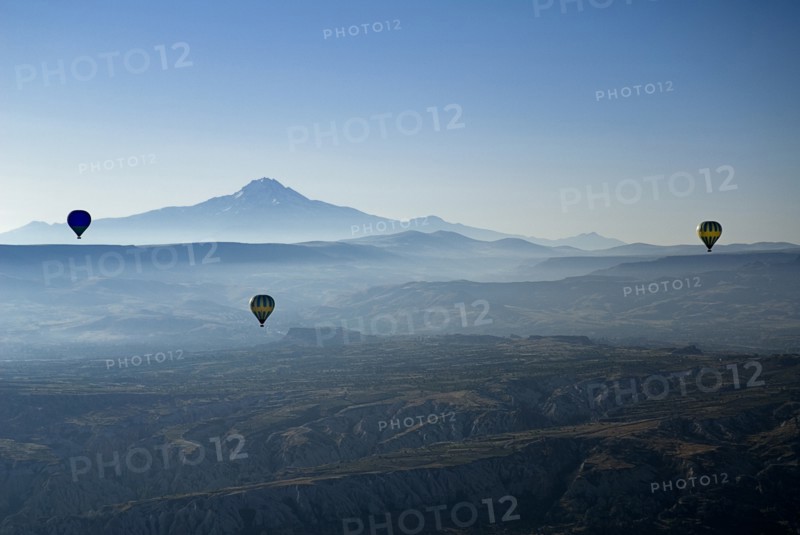 Early morning with hot air balloons in flight mist drifting across landscape and Mount Erciyes in the background. Photo: Hugh Rooney