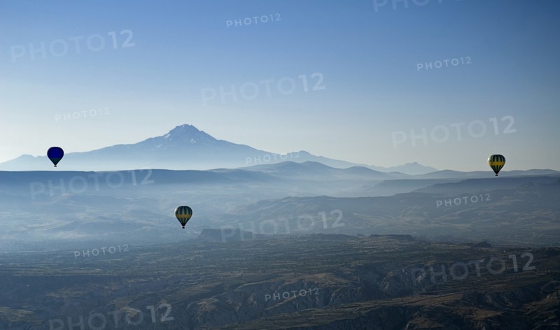 Early morning with hot air balloons in flight mist drifting across landscape and Mount Erciyes in the background. Photo: Hugh Rooney