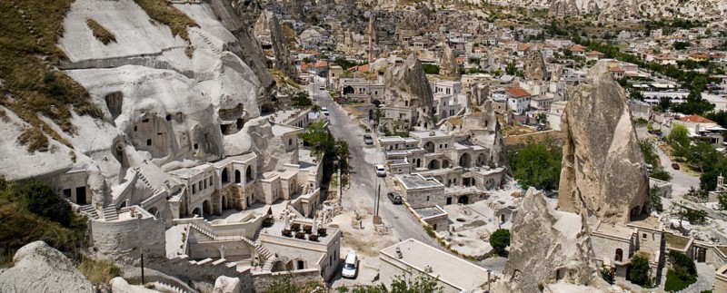 Cave hotel built into white tufa rock of hillside with part view of the town beyond. Photo: Hugh Rooney