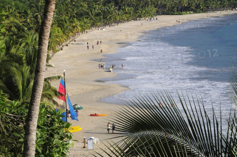 Mexico, Guerrero, Zihuatanejo, View along the shoreline of Playa la Ropa lined with palm trees. A colourful sailboat on sandy beach. 
Photo : Nick Bonetti