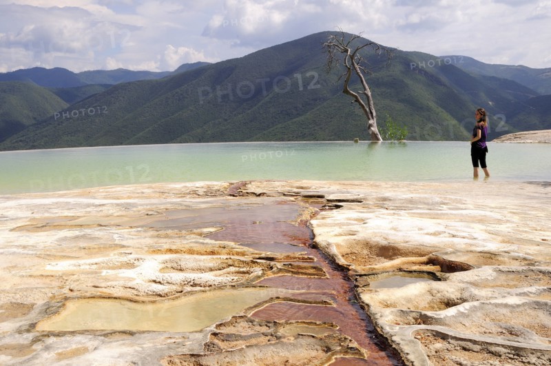 Mexico, Oaxaca, Hierve el Agua, Female tourist standing in limestone pool with view towards mountainous landscape densely covered with trees. 
Photo : Nick Bonetti