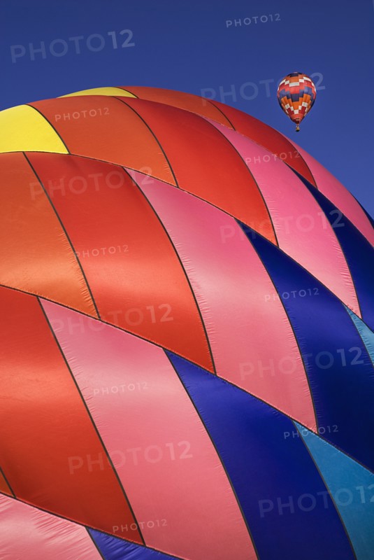 USA, New Mexico, Albuquerque, Annual balloon fiesta colourful hot air balloons with part view of red pink and blue ribbed side of balloon in foreground. 
Photo : Hugh Rooney