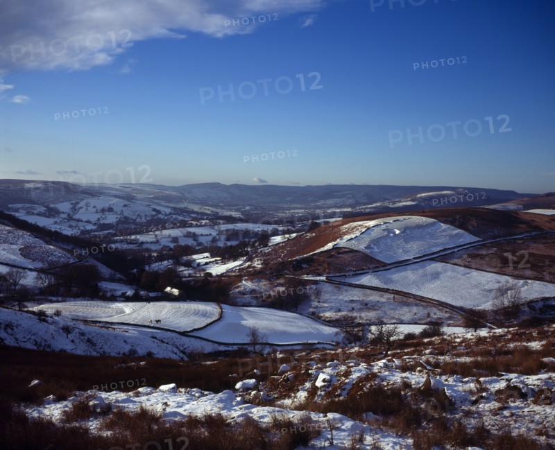 England, Derbyshire, Hathersage, View westwards over snow covered moorland landscape and fields towards Peak District village from Higgartor. 
Photo : Bryan Pickering