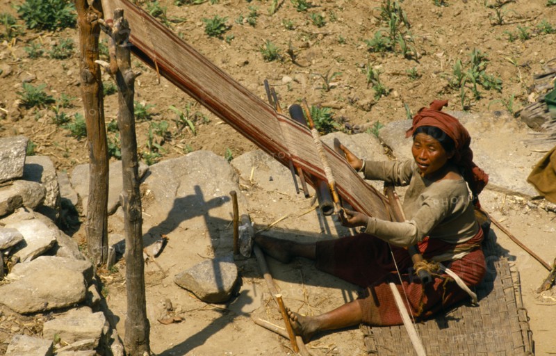 Nepal, East, Gudel, Woman sitting on ground to weave textile on hand loom. 
Photo : Chris Beall