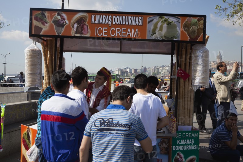 Turkey, Istanbul, Eminonu Ice cream vendor outside the New Mosque with young men waiting to be served. 
Photo : Stephen Rafferty
