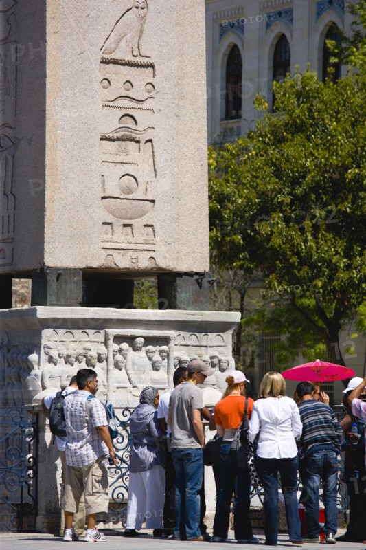 Turkey, Istanbul, Sultanahmet Tourists in the Roman Hippodrome in At Meydani beside Egyptian Obelisk with Hieroglyphics from Luxor and relief at base showing Theodosius I and courtiers. 
Photo : Paul Seheult