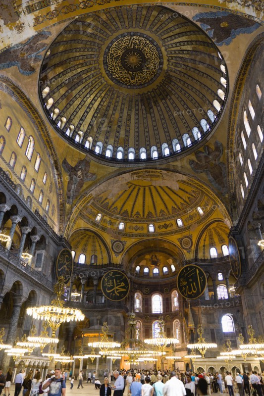 Turkey, Istanbul, Sultanahmet Haghia Sophia Sightseeing tourists beneath the dome with murals and chandeliers in the Nave of the Cathedral. 
Photo : Paul Seheult