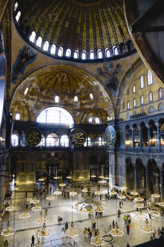 Turkey, Istanbul, Sultanahmet Haghia Sophia Sightseeing tourists beneath the dome with murals and chandeliers in the Nave of the Cathedral. 
Photo : Paul Seheult