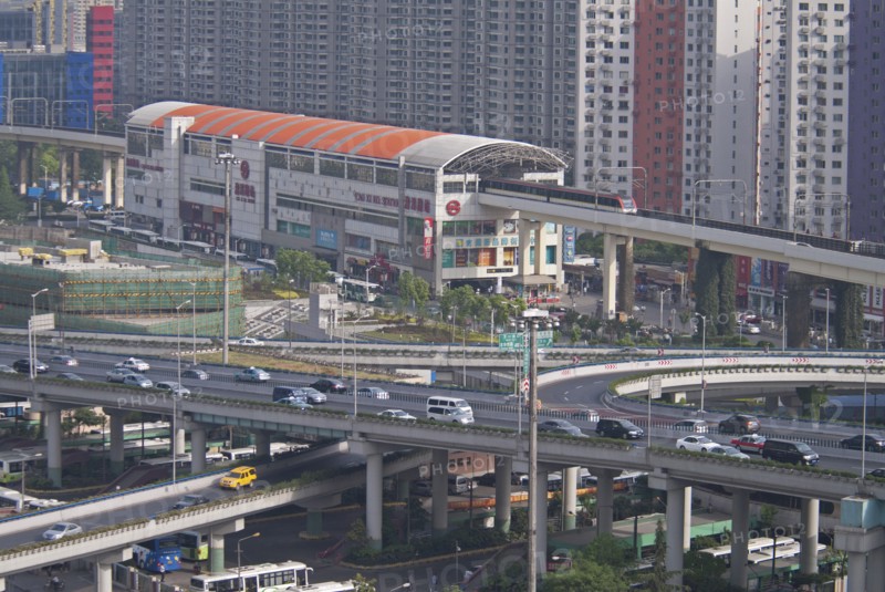 China, Shanghai, Light Railway train leaving Caoxi Road station in south Shanghai in the early morning with cars and buses at spaghetti junction Apartment blocks in background with windows forming a patern. 
Photo : Trevor Page