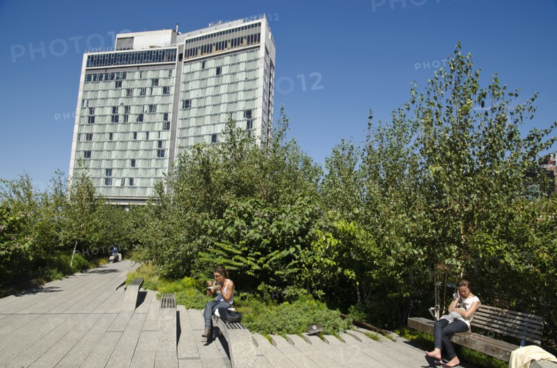USA, New York, Manhattan, West Side High Line Park people realaxing along the benches around 13th street with the Standard Hotel in the background. 
Photo : Jon Burbank