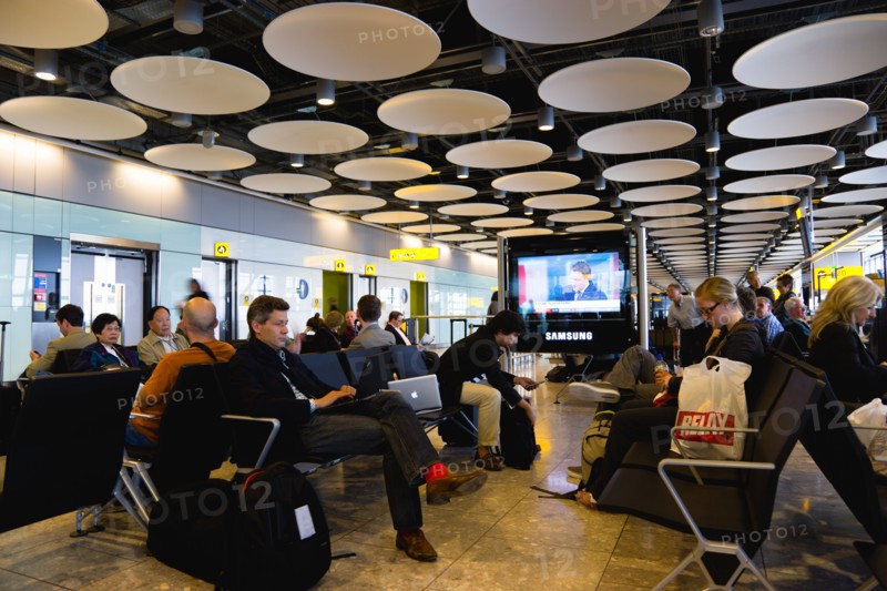 England, London, Heathrow Airport Terminal 5 disc ceiling in departures zone with passengers waiting in seating area at gate. 
Photo : Paul Seheult