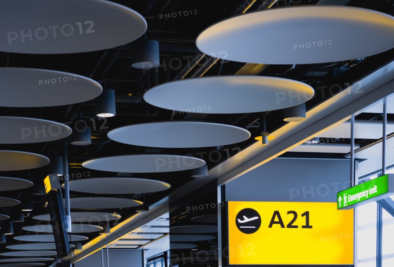 England, London, Heathrow Airport Terminal 5 disc ceiling in departures zone with passengers waiting in seating area at gate. 
Photo : Paul Seheult