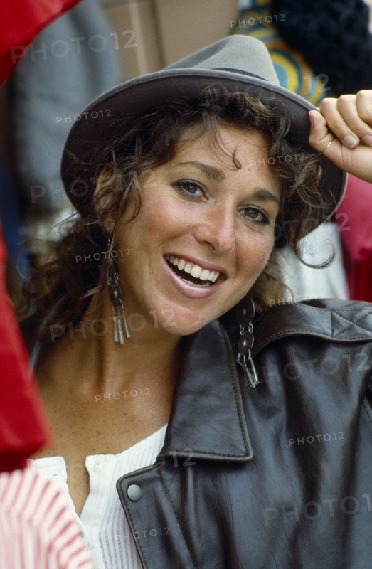 Smiling teen girl wearing hat and leather jacket.