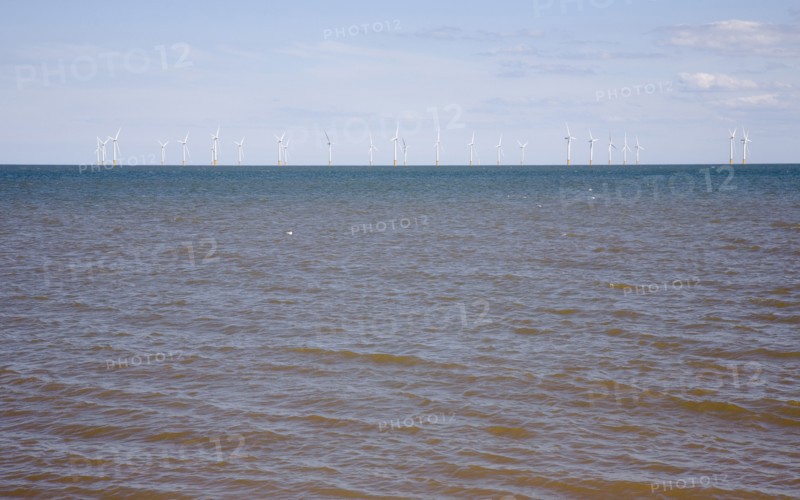 Wind Farm offshore on the horizon showing turbine blades.