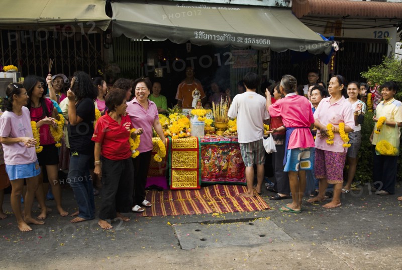 Women in front of Guanyin female Goddess of Mercy statue with offerings for parade celebrating local temple.