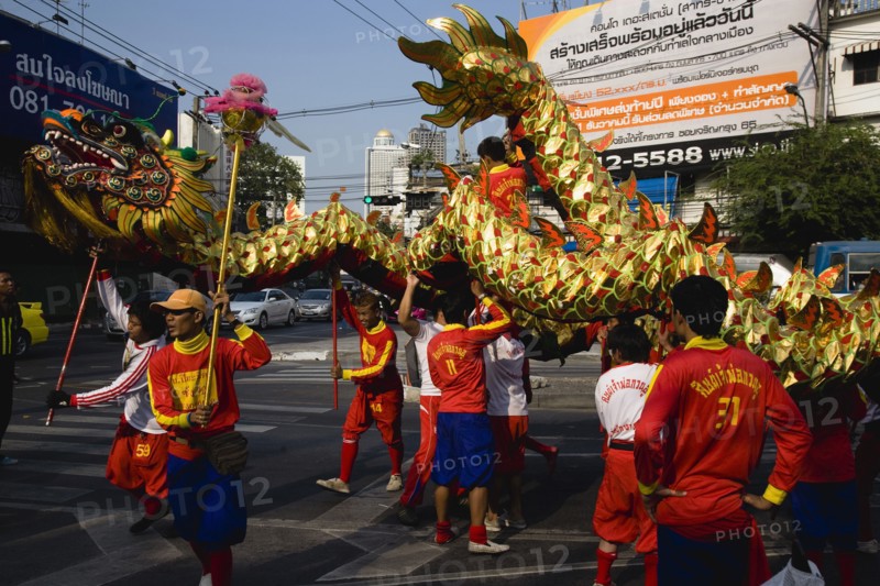young men in costume carry Dragon in parade celebrating local Chinese temple on New Road first paved road in the city.