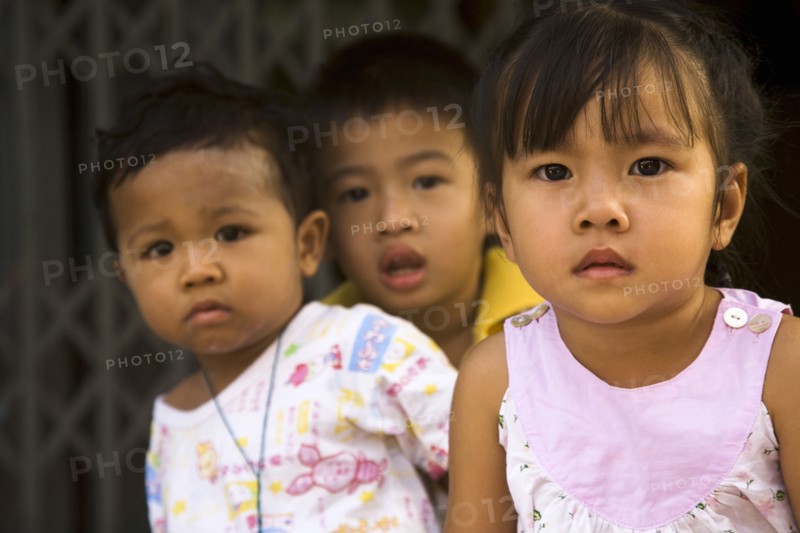 Young children in late afternoon sun in front of shophouse entrance.