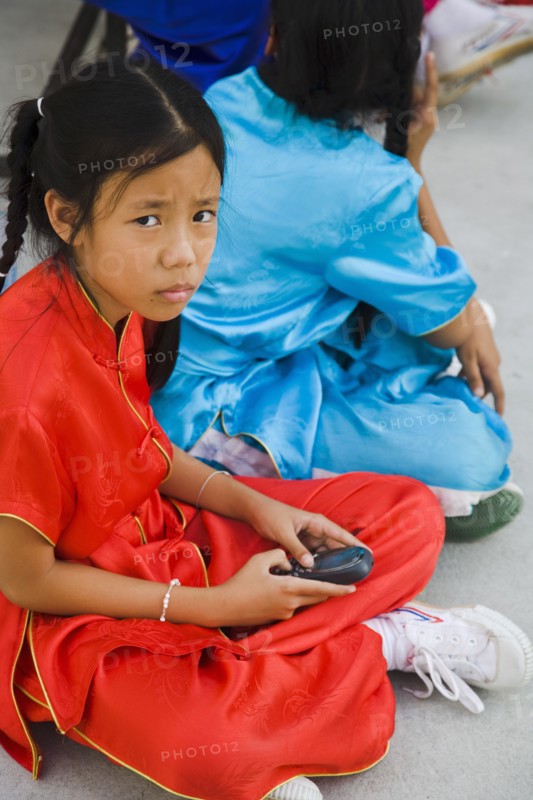 Thai girls using mobile telephone in costume of dance troupe.