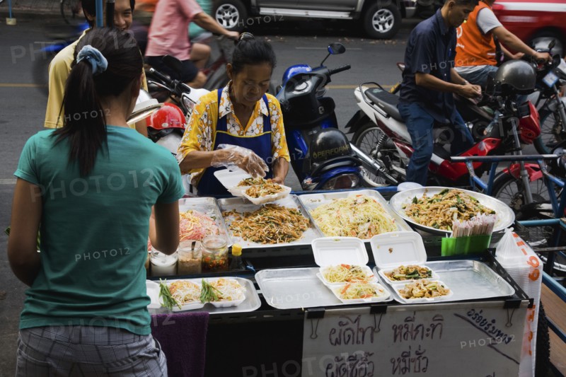Street vendor and daughter sell take away Pad-thai the national fried noodle classic dish.