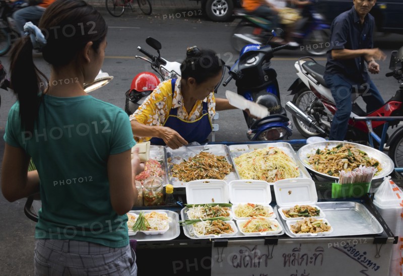 Street vendor and daughter sell take away Pad-thai the national fried noodle classic dish.