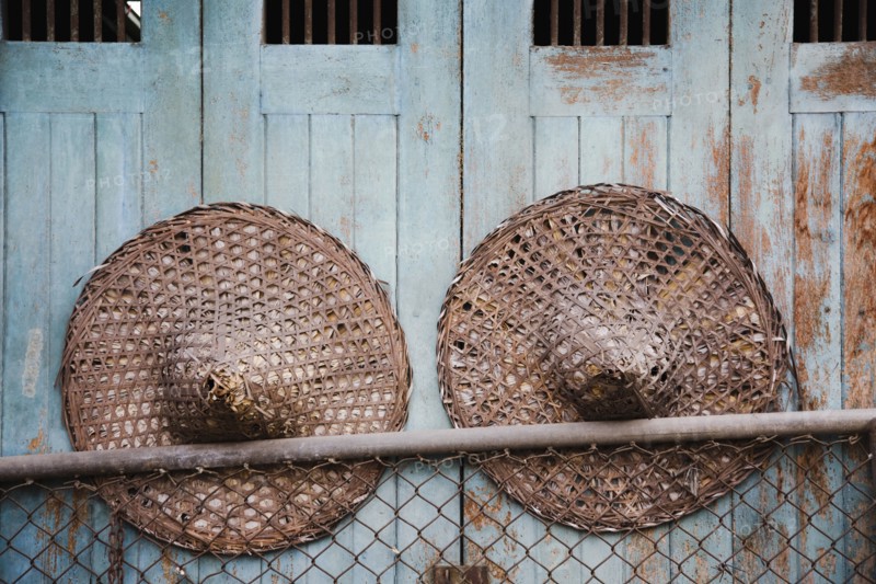 Vintage conical straw hats displayed on wall.