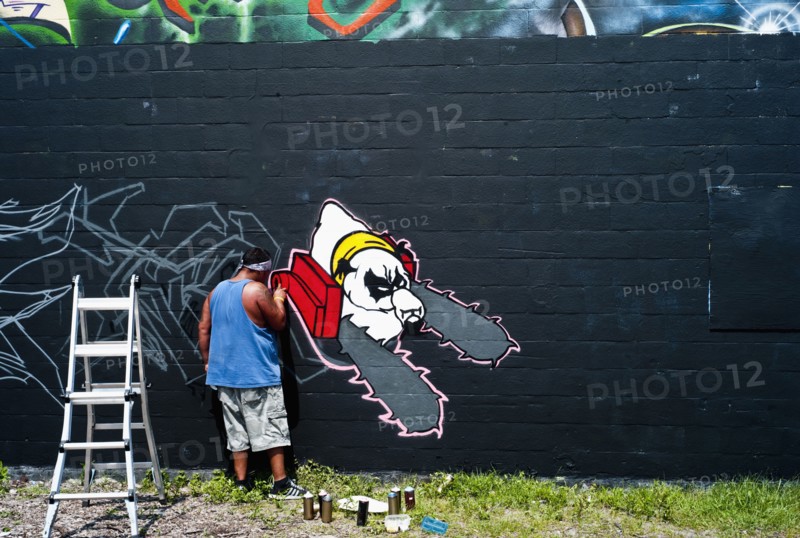 Graffiti artist painting wall.