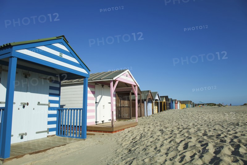 Colourful beach huts along sandy beach.