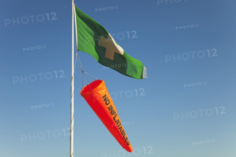 Safety flags. White Cross on Green Flag signalling First Aid Point. Orange No Inflatables windsock.