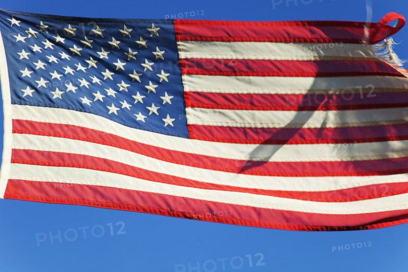United States of America flag flying against a blue sky.