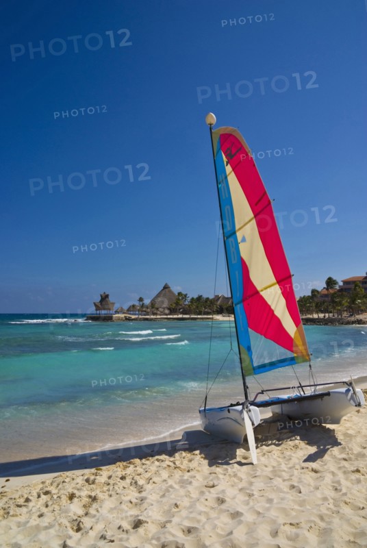View along beach with colourful hobie cat.