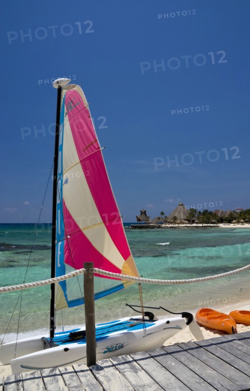 View over beach and bay with colourful hobie cat.