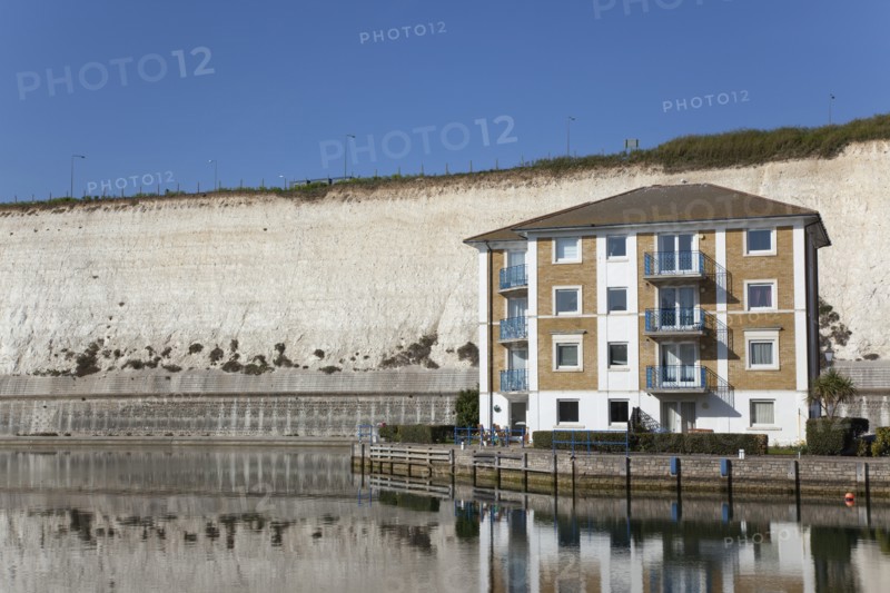 Apartment building in empty marina with chalk cliffs behind.