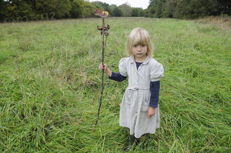 5 year old Eva with stick & leaf flag in a field of grass.