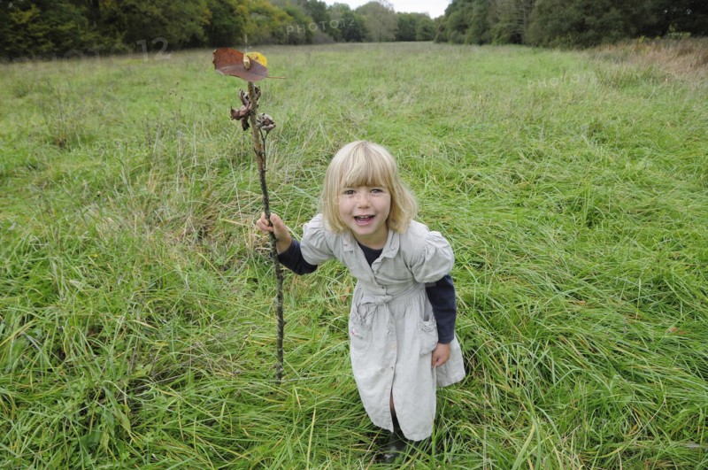5 year old Eva with stick & leaf flag in a field of grass.