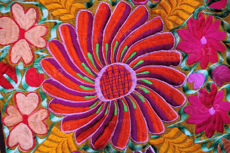Mexico, Bajio, San Miguel de Allende, Detail of brightly embroidered textile in arts shop with flower design in pink red and orange. Photo : Nick Bonetti
