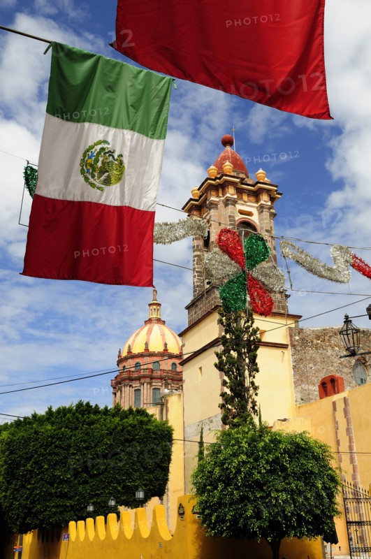 Mexico, Bajio, San Miguel de Allende, Mexican flags and Independence Day decorations hang in foreground of church. Photo : Nick Bonetti
