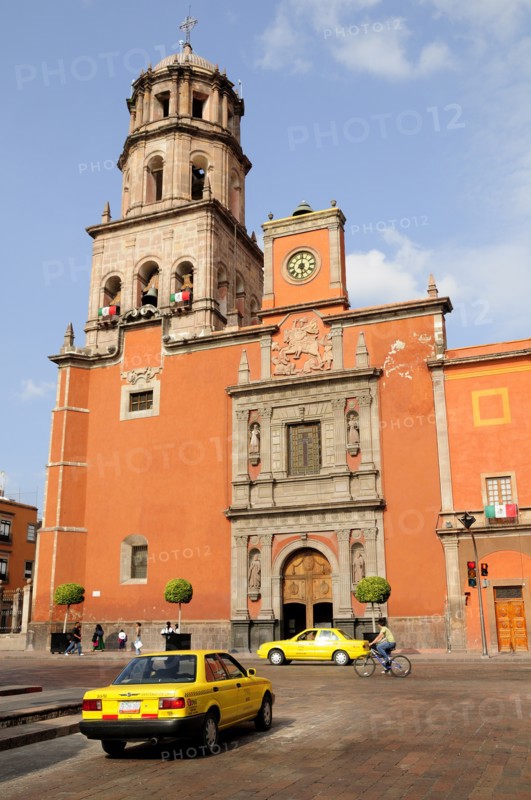Mexico, Bajio, Queretaro, The church of San Francisco brightly coloured exterior facade with taxis and cyclist on road in foreground. Photo : Nick Bonetti